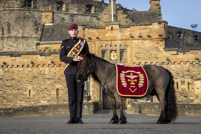 A member of military personnel stands beside Pegasus the pony, the mascot of the Parachute Regiment.