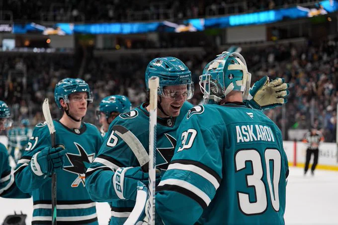 Sam Dickinson congratulating Yaroslav Askarov on the ice in the Sharks' teal jersey 