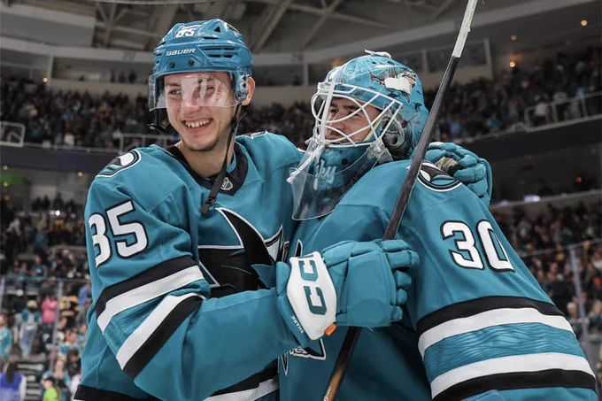 Shakir Mukhamadullin hugging Yaroslav Askarov on the ice in the Sharks' teal jersey 