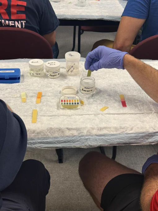 Close up photo of PH strips being dipped into jars to determine the acidity of the chemical.