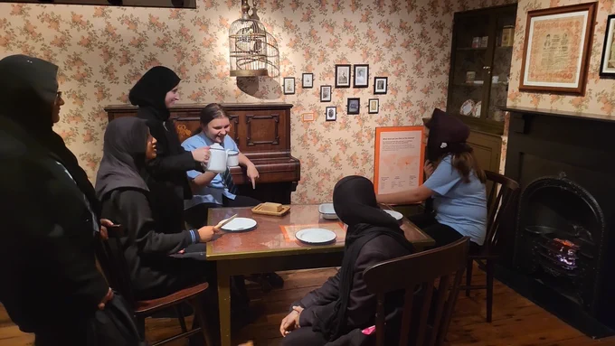 A group of people in an old-fashioned room with a vintage piano, enjoying a moment together. The mood is warm and educational.