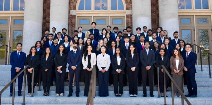 Business Intelligence Group (BIG) student consultants smile on the steps of Foellinger Auditorium with Associate Professor Yoo-Seong Song