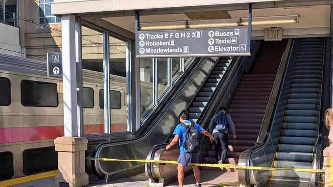 Two commuters climb up stairs which have been blocked off by yellow tape.