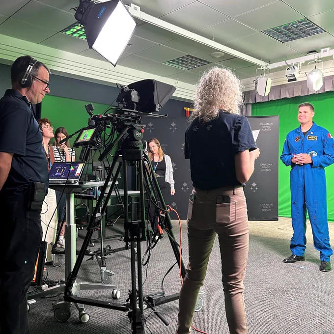 An astronaut standing in front of a green screen during a media production.