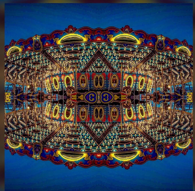 A carousel reflected four times in mirror to create illusion of glass bulbs and neon at dusk