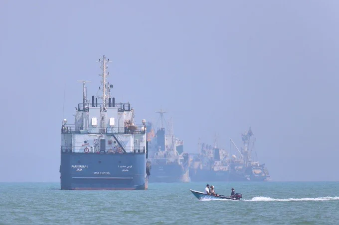 A small motorboat passes anchored vessels in the Strait of Hormuz
