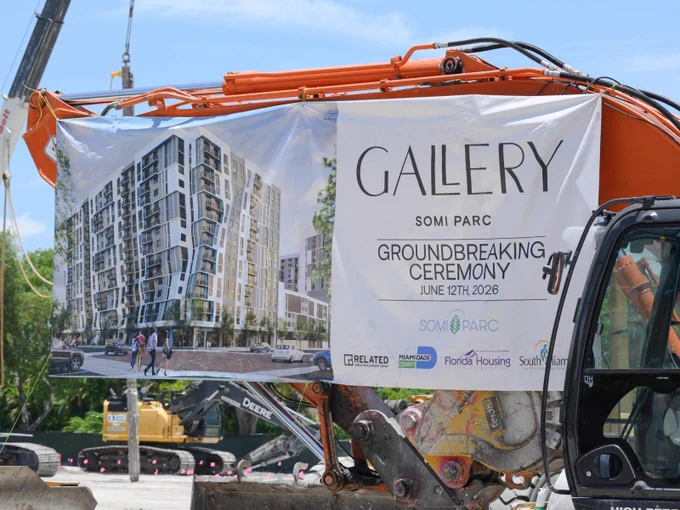 A photo of a large sign draped over a tractor, the sign reads "GALLERY SOMI PARC GROUNDBREAKING CEREMONY JUNE 12TH 2026"