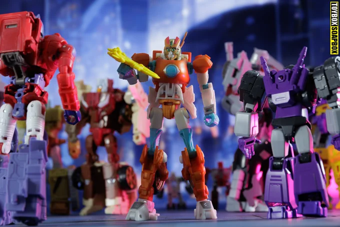 Transformers Rung from the More than Meets the Eye (MTMTE) comics looking at a model ship as Transformers walk past him