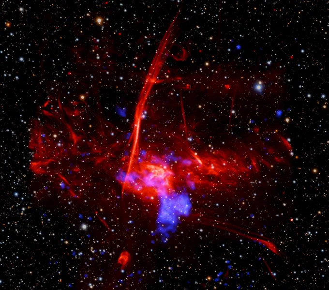 A photo of the site where the potential remains of a supernova. The photo shows an amorphous blob of red light with a spot of blue in the lower center. The background is a diffuse star field in black space. Credit: X-ray: NASA/CXC/UCLA/Z. Zhu et al.; ESA/XMM-Newton; Optical: PanSTARRS; Radio: MeerKAT; Infrared (JWST): NASA/ESA/CSA/STScI; Image Processing: NASA/CXC/SAO/L. Frattare and P. Edmonds