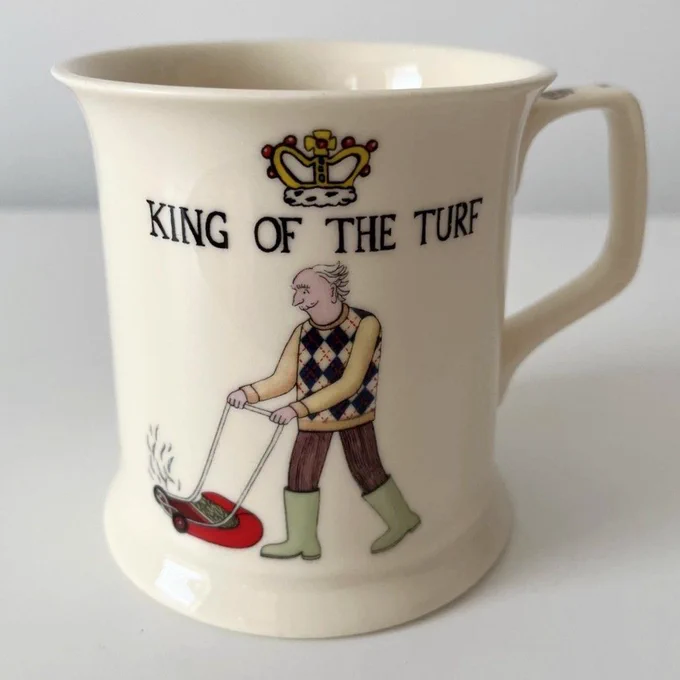 Past Times bone china mug depicting a man in a handsome sweater vest mowing a lawn, under text reading "king of the turf".