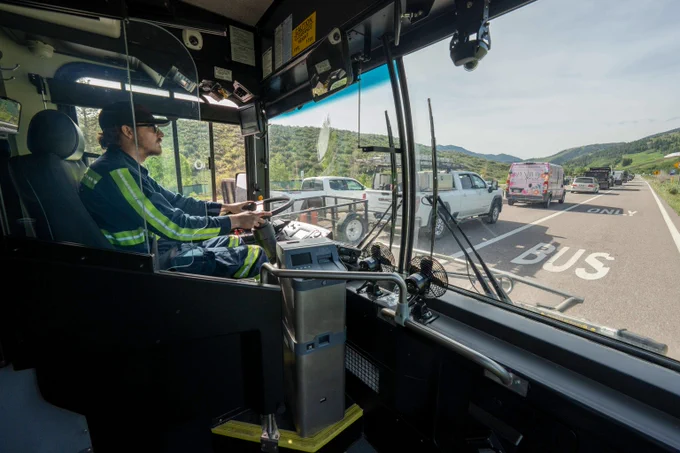 bus driver driving a bus next to traffic in the left lanes. the bus is driving in the clear bus lane. 