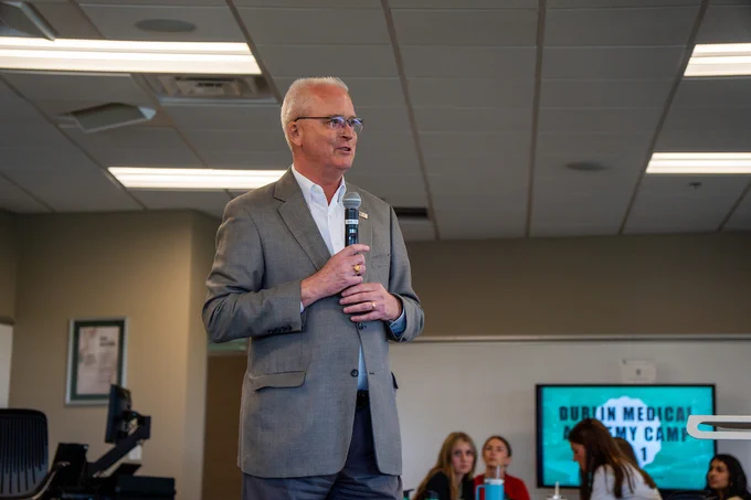 William Burke, DO, dean of the Dublin campus, speaks into a microphone while standing in front of high school students during the 2025 Medical Academy program.