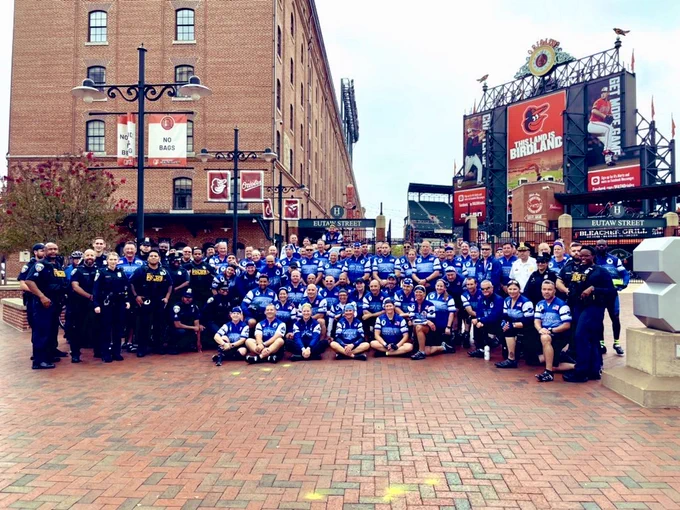 Group of law enforcement officers and athletes gathered in front of Oriole Park at Camden Yards for a Unity bike event.