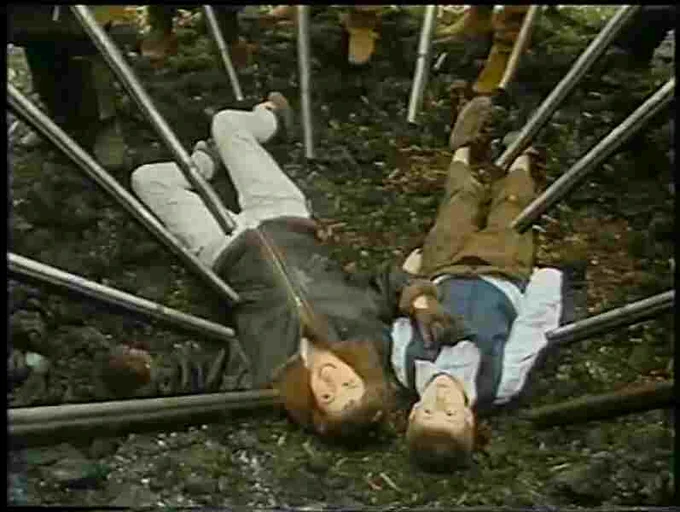 Woman and boy lie on the ground, surrounded by muskets.