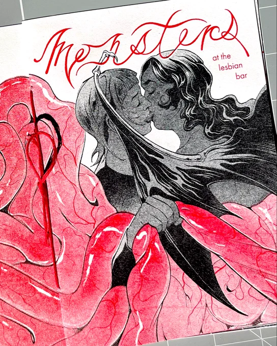 Photo of a zine cover. Two characters are kissing, and one is pulling on the others intestines. Text reads: Monsters at the lesbian bar.
