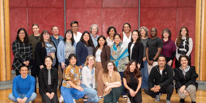 A group of 25 people pose for a photo at the National Museum of the American Indian's Cultural Resources Center. The first row of people is kneeling or sitting, while rows two and three have people standing.