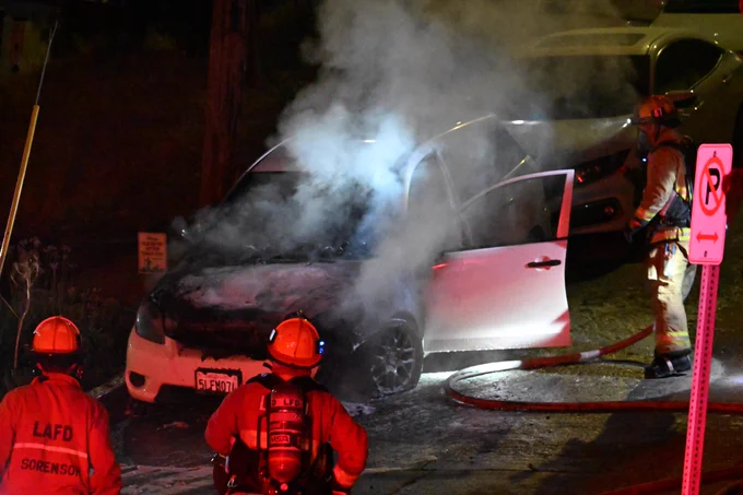 Firefighters knocked down the bulk of the fire but determine that the hood needs to be opened to fully put the fire out.