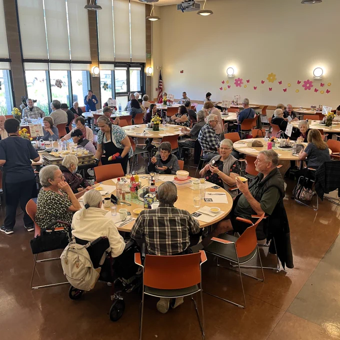 a large dining hall full of people seated at round tables.