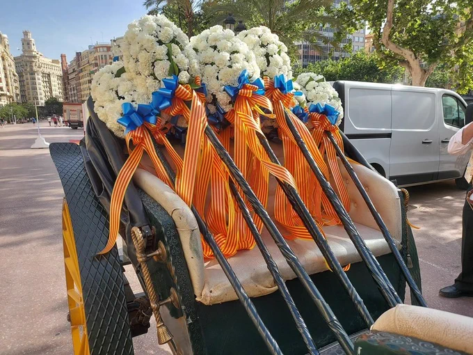 Ramos blancos con lazos azules y largas cintas amarillas y rojas sobre el asiento de un carruaje.