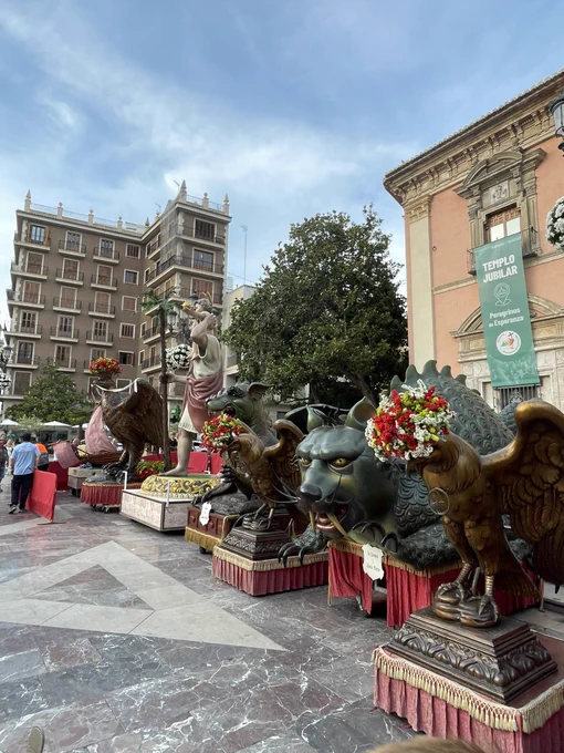 Bestiari del Corpus expuesto en la plaza de la Reina. En la imagen se ve varias figuras festivas gigantes con flores junto a un edificio con pancarta que dice "Templo Jubilar".