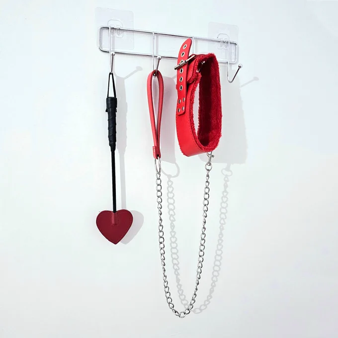 Cover art for Darling Gails' single "Ben Dover" featuring a red spade BDSM paddle and a red fuzzy collar with leash attached hanging from hooks on a white wall.
