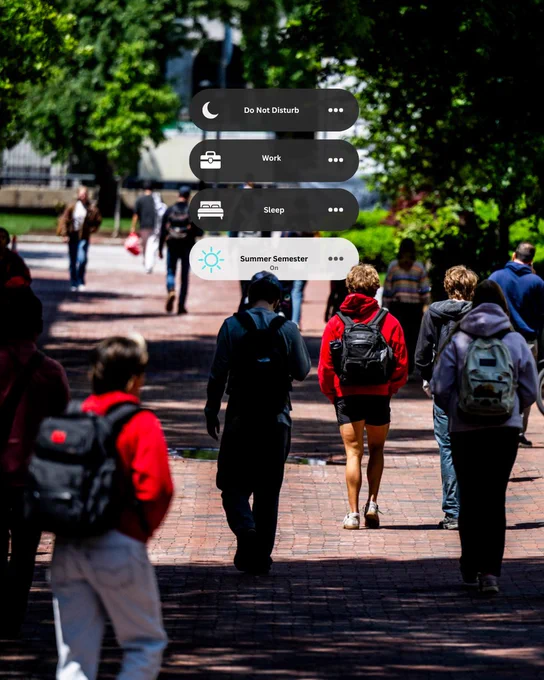 Young adults walk on a sun-dappled brick path with backpacks. 