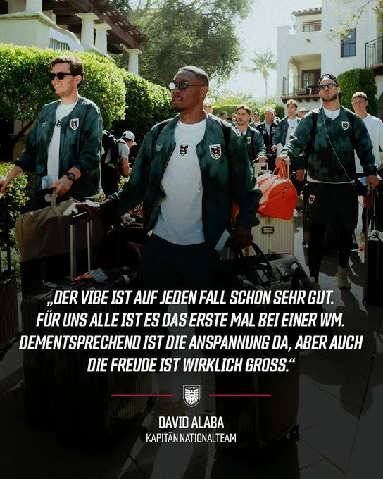 Eine Gruppe von Menschen in Sporttrikots mit dem Wappen des österreichischen Fußballverbands auf dem Weg durch eine Umgebung mit Gebäuden.