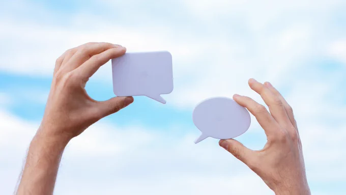 Two hands hold a dialog bubble each. 