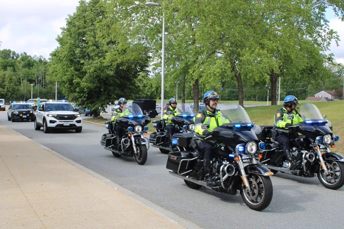 Police officers riding motorcycles in a formation, followed by police vehicles lead the way for the Special Olympics Massachusetts Torch Run.