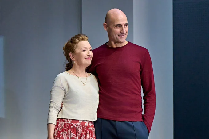 A photo showing two figures in casual attire embracing in a grey office space 