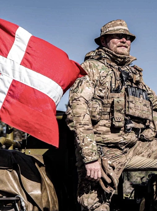 Un soldat danois se tenant devant un drapeau danois. 