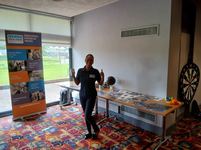 Malika standing next to our Sporting Memories stall at Leeds Dementia Friendly Event