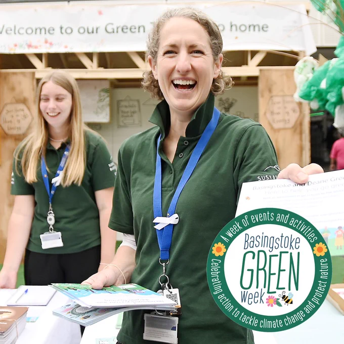 A woman laughing while holding leaflets at a Basingstoke Green Week event.