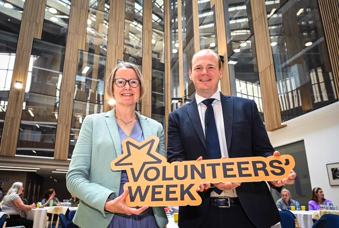 Minister Lyons and Denise Hayward holding a Volunteers’ Week sign at Volunteer Now’s Volunteers’ Week at Ulster University, Belfast.