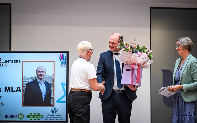 Minister Lyons presenting a bouquet of flowers to Wenda Gray, a Volunteer Now staff member, in recognition of her retirement following 17 years of service.