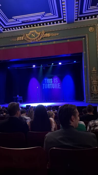 It’s the view from our seats of the stage and the ‘This Is Torture’ show title on the backdrop.