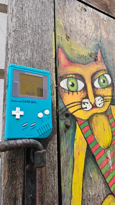 Ein Game Boy neben einer aufgemalten Katze