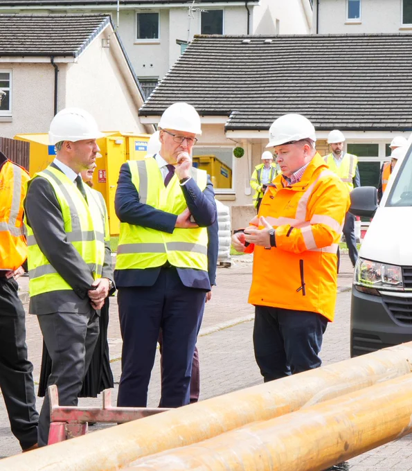 First Minister John Swinney and Justice Secretary Neil Gray speaking to a man at Coalsnaughton. All are wearing hard hats and hi vis jackets. 