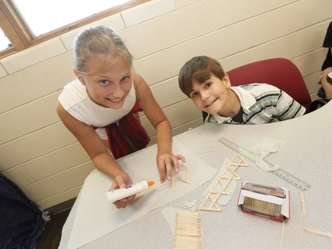 Students smile at camera while working on a tooth pic construction project.