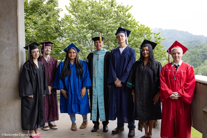 Dr. Jackson stands in the center of graduates in various colored graduation caps and gowns