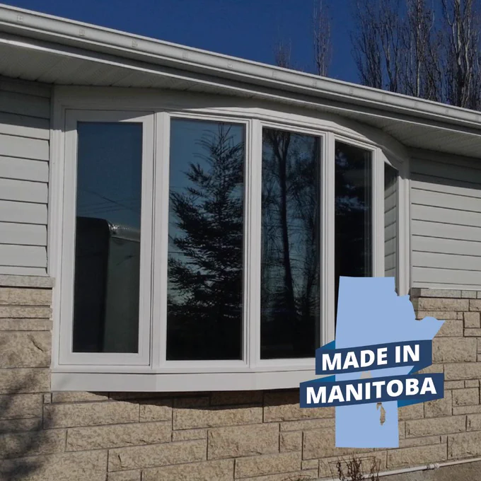 White custom bow window installed on Manitoba home exterior with large glass panels designed for energy efficiency and natural light.