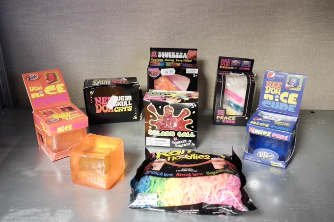 A collection of seized squishy toys including Doh-N-Ice, Nee Doh cubes, and Rar Noodles.