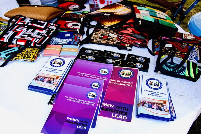 This image showcases an exhibition display table featuring advocacy materials and handcrafted products,