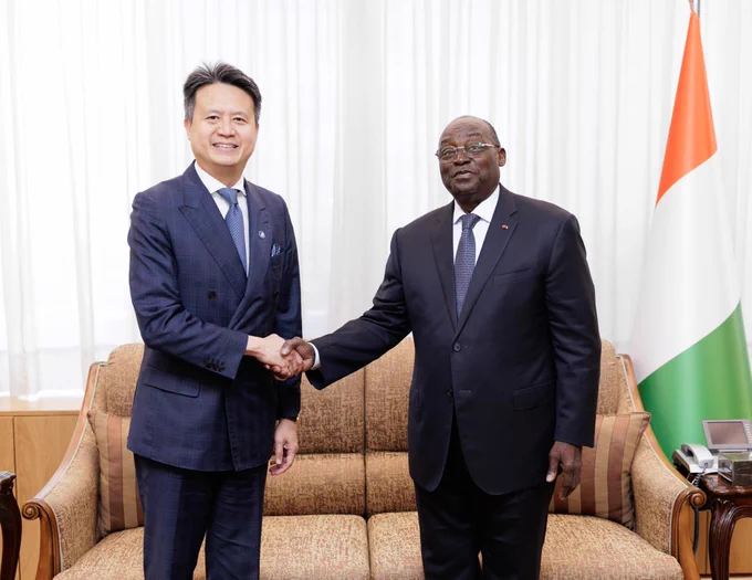 WIPO Director General Daren Tang shaking hands with Tiémoko Meyliet Koné, Vice President of Côte d'Ivoire. In the background, Côte d'Ivoire’s national flag.