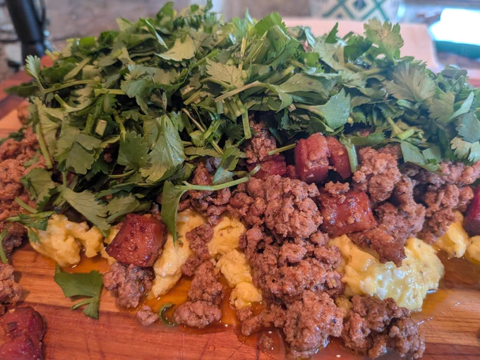 Eggs topped with ground beef, bacon, and cilantro