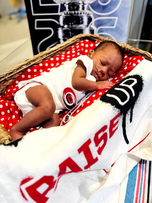 Several UNC Health Rex NICU babies wear Carolina Hurricanes-themed outfits while resting in their bassinets. Cutouts of Stormy, the Hurricanes mascot, and the Stanley Cup are displayed beside them as they celebrate the team's win.