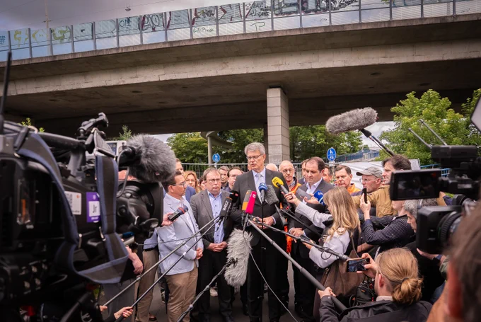 Bundesverkehrsminister Patrick Schnieder ist vor Ort an der gesperrten Bonner Rheinbrücke. Auf dem Foto steht er inmitten zahlreicher Journalistinnen und Journalisten. 