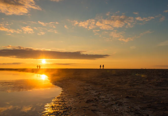 People walking along the beach at Rouge National Urban Park in Ontario during a sunset. Photo by Parks Canada: Scott Munn.