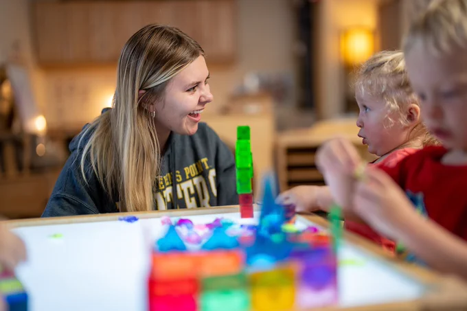 Student in classroom interacting with children. 