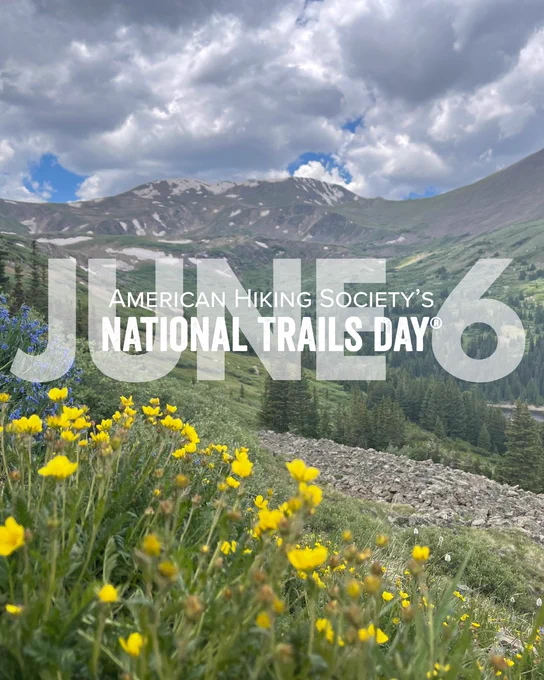 Wildflowers bloom in a mountainous landscape under a cloudy sky, celebrating National Trails Day on June 6.
